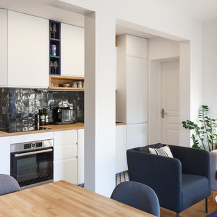 Cette photo montre une petit cuisine ouverte linéaire tendance avec un évier posé, un placard à porte plane, des portes de placard blanches, un plan de travail en bois, une crédence noire, un électroménager en acier inoxydable, aucun îlot, un sol multicolore, un plan de travail marron, une crédence en carreau de terre cuite et un sol en carreaux de ciment.