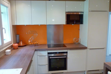 Imagen de cocina clásica renovada grande con fregadero bajoencimera, armarios con paneles lisos, puertas de armario blancas, encimera de madera, salpicadero naranja, salpicadero de metal, electrodomésticos de acero inoxidable, suelo de baldosas de cerámica y dos o más islas