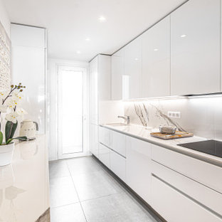 Design ideas for a mid-sized contemporary galley separate kitchen in Nice with an integrated sink, beaded inset cabinets, white cabinets, solid surface benchtops, white splashback, panelled appliances, ceramic floors, grey floor and white benchtop.