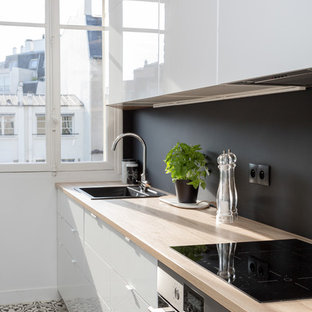 Inspiration for a mid-sized contemporary single-wall separate kitchen in Paris with wood benchtops, no island, a drop-in sink, flat-panel cabinets, white cabinets, black splashback, slate splashback, stainless steel appliances, slate floors, multi-coloured floor and beige benchtop.