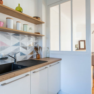 Aménagement d'une cuisine scandinave fermée avec un évier posé, un placard à porte plane, des portes de placard blanches, un plan de travail en bois et un plan de travail marron.