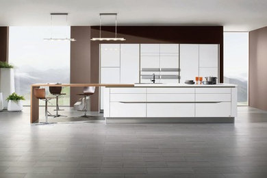 ナントにある巨大なコンテンポラリースタイルのおしゃれなキッチン (白いキャビネット、パネルと同色の調理設備) の写真