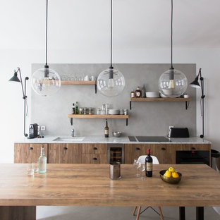 Exemple d'une grand cuisine ouverte linéaire industrielle avec un évier encastré, un placard à porte plane, des portes de placard en bois brun, une crédence grise, béton au sol, un sol gris, un électroménager noir et aucun îlot.