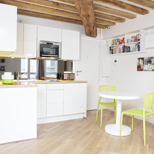 Exemple d'une petit cuisine américaine scandinave en L avec un placard à porte plane, des portes de placard blanches, un sol en bois clair et aucun îlot.