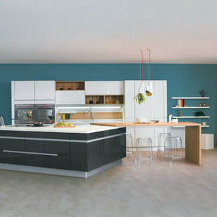 Inspiration pour une grand cuisine ouverte parallèle design avec des portes de placard blanches, une crédence blanche, un électroménager en acier inoxydable et un îlot central.