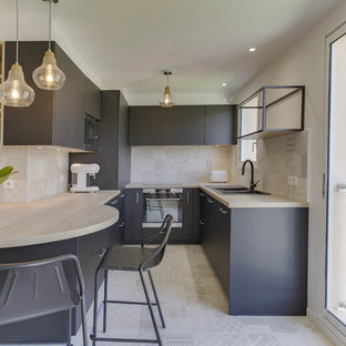 Idée de décoration pour une cuisine linéaire design fermée et de taille moyenne avec un évier 2 bacs, un placard à porte plane, des portes de placard noires, un plan de travail en stratifié, une crédence beige, une crédence en carreau de terre cuite, un électroménager en acier inoxydable, un sol en carrelage de céramique, aucun îlot et un sol beige.