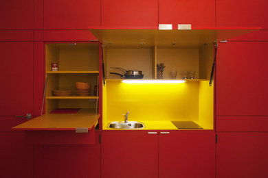 Modelo de cocina lineal contemporánea pequeña cerrada sin isla con fregadero de un seno, puertas de armario rojas, salpicadero amarillo y encimeras amarillas