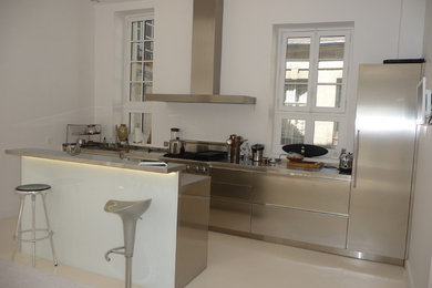 Imagen de cocina comedor minimalista de tamaño medio con encimera de acero inoxidable, suelo de cemento, una isla y suelo blanco