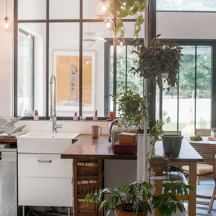 Cette image montre une cuisine urbaine en L fermée et de taille moyenne avec un évier de ferme, un plan de travail en bois, une crédence blanche, un sol en carrelage de céramique et aucun îlot.