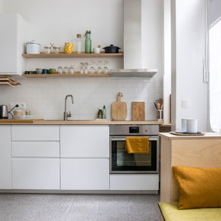 Exemple d'une petit cuisine ouverte linéaire tendance avec un évier posé, un placard à porte plane, des portes de placard blanches, un plan de travail en bois, une crédence blanche, une crédence en carrelage métro, un électroménager en acier inoxydable, aucun îlot, un sol gris et un plan de travail beige.
