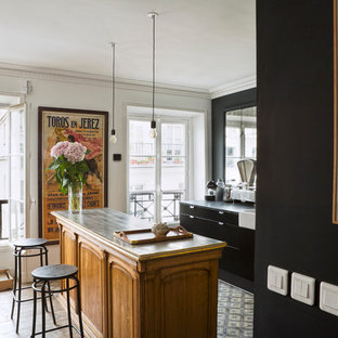 Réalisation d'une cuisine ouverte parallèle design de taille moyenne avec des portes de placard noires, un sol en ardoise et un îlot central.