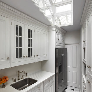 This is an example of a small classic galley enclosed kitchen in London with a submerged sink, white cabinets, white splashback, stainless steel appliances, white floors, white worktops, raised-panel cabinets and no island.