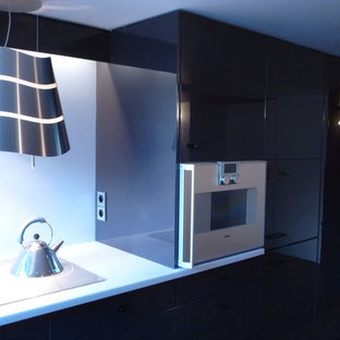 Idée de décoration pour une petit cuisine ouverte linéaire design avec un évier encastré, un placard à porte affleurante, des portes de placard violettes, un plan de travail en surface solide, une crédence bleue, un électroménager encastrable, un sol en bois clair et un plan de travail bleu.