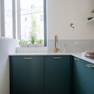 Ispirazione per una cucina a L tropicale con lavello a vasca singola, ante lisce, ante verdi, parquet chiaro, pavimento beige e top grigio