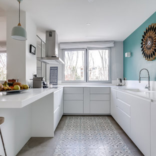Aménagement d'une cuisine contemporaine en U avec un évier intégré, un placard à porte plane, des portes de placard blanches, une péninsule, un sol gris et un plan de travail blanc.