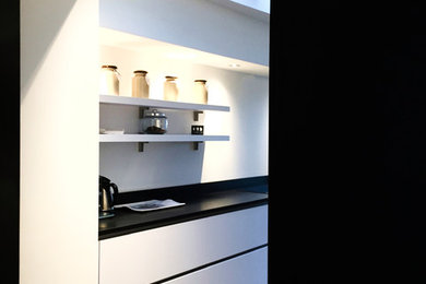 Large contemporary single-wall open plan kitchen in Lille with a submerged sink, flat-panel cabinets, granite worktops, black splashback, marble splashback, stainless steel appliances, ceramic flooring, an island, black floors and black worktops.