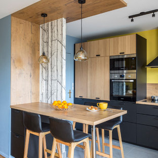 Exemple d'une cuisine américaine tendance en L de taille moyenne avec un plan de travail en bois, une crédence en bois, un îlot central et un sol gris.