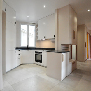 Design ideas for a small transitional u-shaped open plan kitchen in Paris with an integrated sink, beaded inset cabinets, white cabinets, solid surface benchtops, blue splashback, black appliances, ceramic floors, grey floor and blue benchtop.