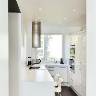 This is an example of a small contemporary u-shaped separate kitchen in Paris with stainless steel appliances, ceramic floors, no island, flat-panel cabinets and white cabinets.