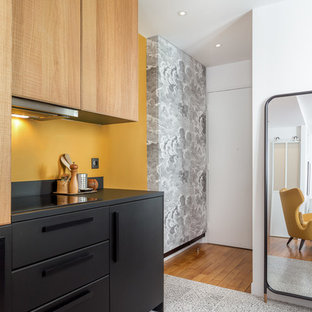 Inspiration pour une cuisine design avec un placard à porte plane, des portes de placard noires, une crédence jaune, un sol multicolore et un plan de travail noir.