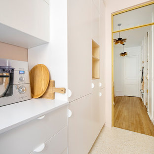Inredning av ett shabby chic-inspirerat avskilt, litet rosa rosa parallellkök, med en undermonterad diskho, luckor med profilerade fronter, bänkskiva i kvartsit, vitt stänkskydd, stänkskydd i terrakottakakel, integrerade vitvaror, terrazzogolv och vitt golv