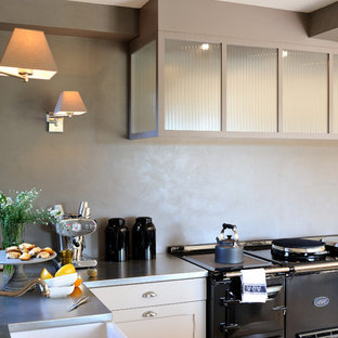 Exemple d'une cuisine américaine éclectique en L avec un plan de travail en inox, une crédence grise, un électroménager en acier inoxydable et aucun îlot.