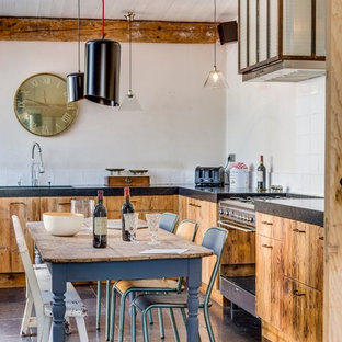 Modelo de cocina comedor en L, ecléctica, de tamaño medio, sin isla, con armarios con paneles lisos, puertas de armario de madera clara, salpicadero blanco, fregadero bajoencimera, salpicadero de azulejos de cemento y electrodomésticos negros