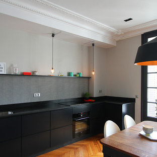 Inspiration pour une cuisine américaine design en L de taille moyenne avec des portes de placard noires, aucun îlot et une crédence grise.