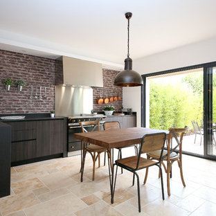 Inspiration pour une cuisine ouverte méditerranéenne en L avec un évier 1 bac, un placard à porte plane, des portes de placard en bois sombre, une crédence rouge, une crédence en brique, un électroménager noir, aucun îlot et un sol beige.