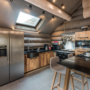 Inspiration pour une cuisine ouverte chalet en L de taille moyenne avec un évier de ferme, un placard à porte plane, des portes de placard en bois sombre, un plan de travail en quartz, une crédence noire, une crédence en bois, un électroménager en acier inoxydable, une péninsule et un sol gris.