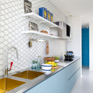 Aménagement d'une cuisine ouverte linéaire contemporaine de taille moyenne avec un évier 2 bacs, un placard à porte plane, des portes de placard bleues, un plan de travail en inox, une crédence multicolore et aucun îlot.