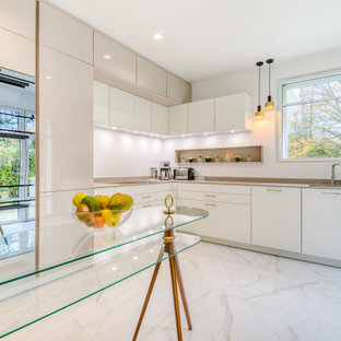 Inspiration pour une très grand cuisine design en L fermée avec un évier encastré, un placard à porte affleurante, des portes de placard beiges, un plan de travail en surface solide, une crédence blanche, un sol en carrelage de céramique et un plan de travail beige.