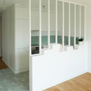 This is an example of a small contemporary u-shaped open plan kitchen in Paris with an undermount sink, flat-panel cabinets, white cabinets, quartzite benchtops, green splashback, ceramic splashback, panelled appliances, cement tiles, no island, turquoise floor and white benchtop.