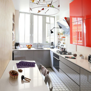 Cette image montre une cuisine américaine design en L de taille moyenne avec un évier encastré, un placard à porte plane, des portes de placard grises et aucun îlot.