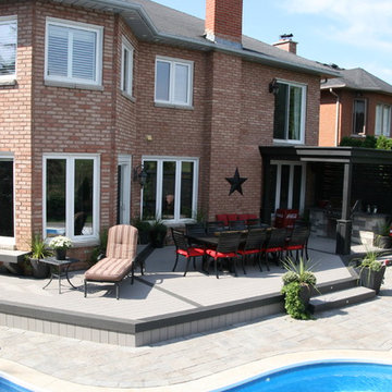 A large low maintenance deck with a BBQ area with a shade roof over it.