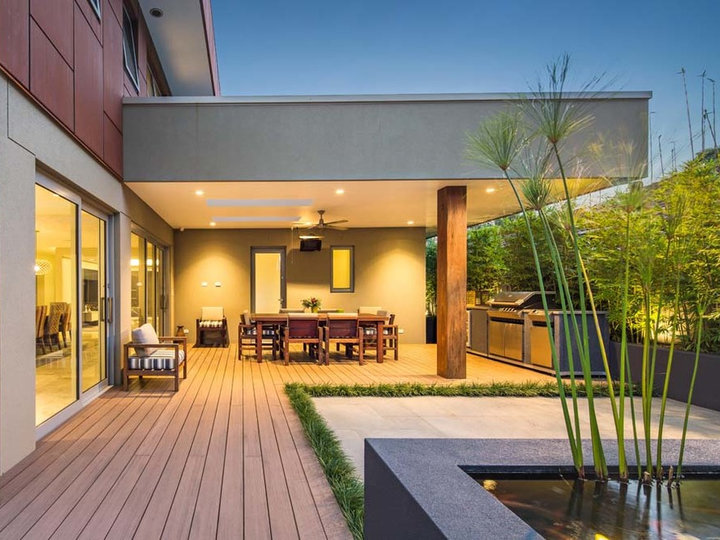 Large trendy side yard outdoor kitchen deck photo with a roof extension