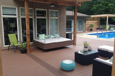 Deck - large modern backyard deck idea in Kansas City with a pergola
