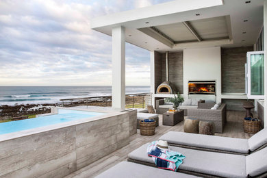 Large beach style backyard deck photo in Other with a fireplace and a roof extension