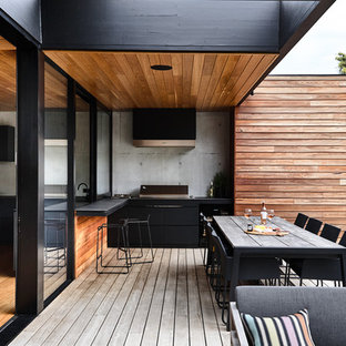Ispirazione per una terrazza minimal di medie dimensioni e dietro casa con un tetto a sbalzo