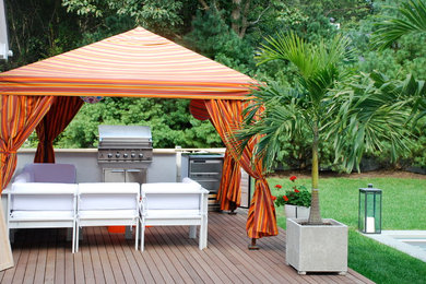 Example of a large trendy backyard outdoor kitchen deck design in New York with an awning