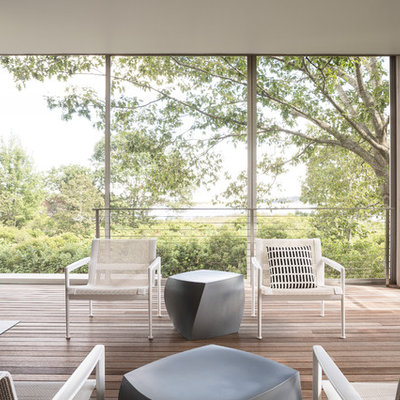 Example of a trendy deck design in Portland Maine with a fire pit and a roof extension