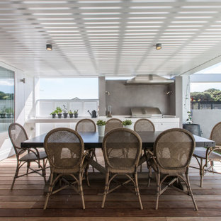 Large beach style backyard deck in Perth with an outdoor kitchen and a roof extension.
