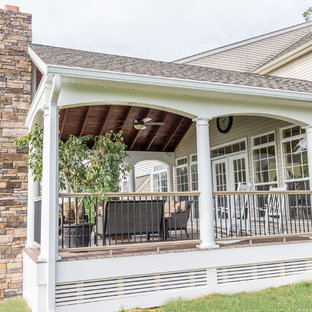 Inspiration pour une grande terrasse arrière traditionnelle avec une extension de toiture et jupe de finition.