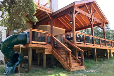 Inspiration for a large rustic backyard deck remodel in Other with a roof extension