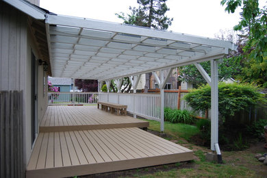 Large beach style backyard deck photo in Portland with a pergola