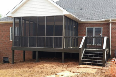 Example of a large classic backyard deck design in Other with a roof extension