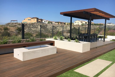 Example of a minimalist backyard deck design in San Diego with a pergola