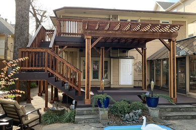 This is an example of a large rustic back terrace in Dallas with a pergola.