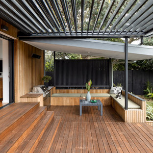 Mid-sized contemporary backyard and ground level deck in Sydney with a pergola.