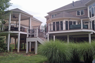 Exempel på en stor klassisk terrass på baksidan av huset, med takförlängning